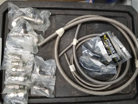 1949 Jeep Wagoneer - Various automotive brake lines and fittings are laid out on a dark surface, some still in their original packaging.
