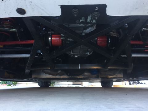2015 Subaru Impreza - The underside of a vehicle is shown, revealing the drivetrain and suspension system with red CV joint boots.