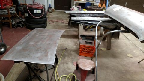 1979 Chevrolet Camaro - Car parts, likely a hood and fender, are laid out in a garage for restoration.