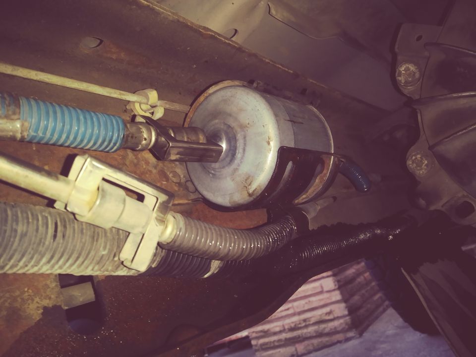 Inline fuel filter mounted under a vehicle with fuel and brake lines