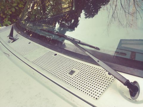 1996 Ford Bronco - Close-up view of the windshield wiper assembly and the perforated cowl vent on a vehicle.