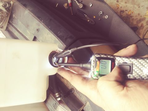 1996 Ford Bronco - Testing a fluid reservoir with a digital multimeter, showing 0.0 volts.