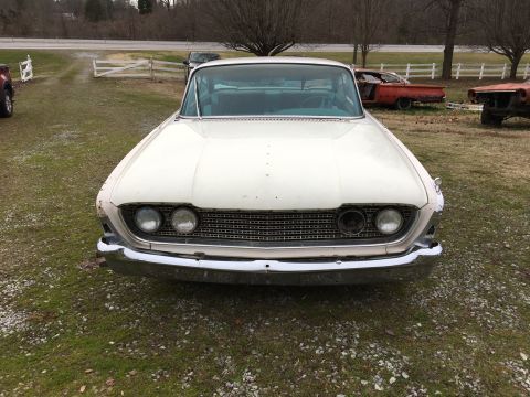 1960 Ford Starliner - Front view of a white 1959 Ford Fairlane 500 Galaxie parked outdoors with other vehicles in the background.