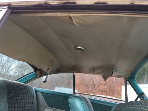 1960 Ford Starliner - Interior view of a car with a damaged headliner and teal upholstery, seen from the rear seats.