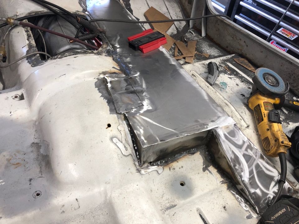 Vehicle interior floor with metal patches and welding, angle grinder visible