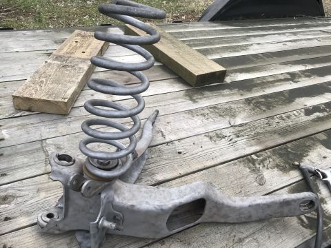 1994 Ford Bronco - A suspension component, likely from a truck or SUV, is shown with its coil spring resting on wooden planks.