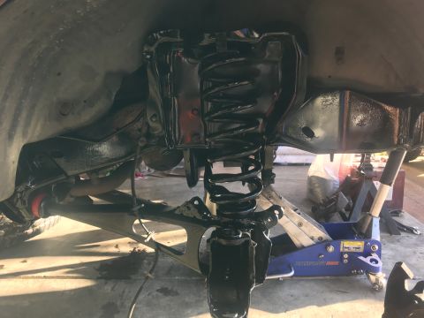 1994 Ford Bronco - The vehicle's front suspension components have been recently painted black and are being worked on with a hydraulic jack and jack stands.