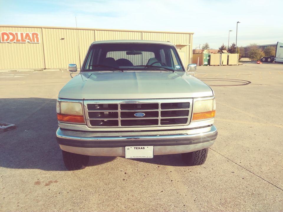 Front view of a silver Ford Bronco parked in a lot. Texas license plate visible