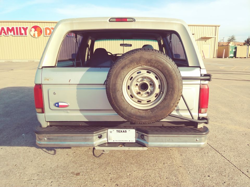 Rear view of a 1992 Ford Bronco with a spare tire mounted on the back. Texas license plate visible