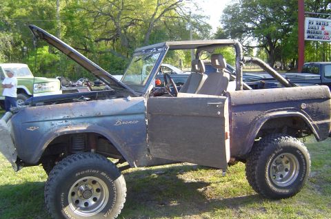 1974 Ford Bronco - This 1974 Ford Bronco is shown with its hood up and driver's door open, parked outdoors.