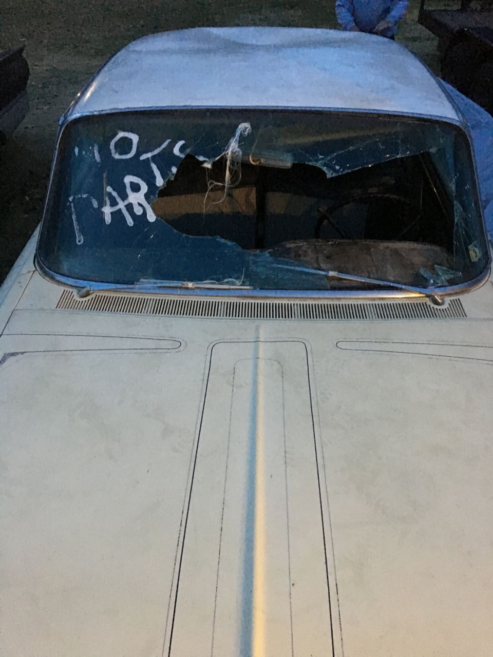White car's cracked windshield with "10 PARTS" written on it