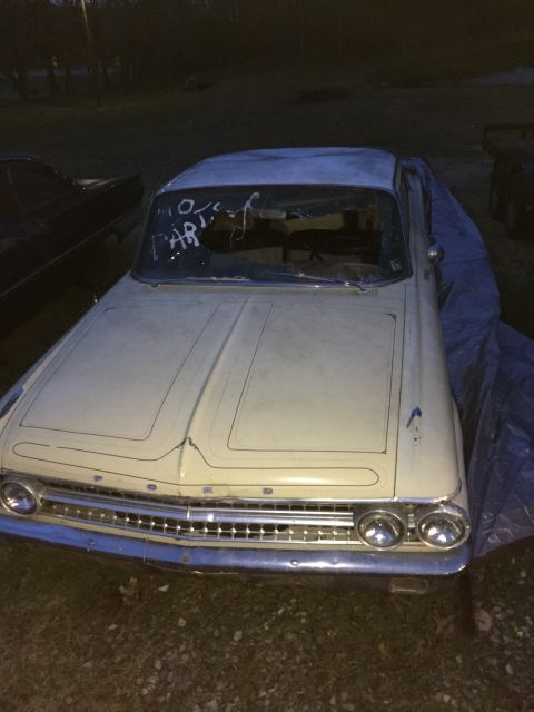 1961 Ford Starliner - Front view of a 1961 Ford Starliner, partially covered with a tarp, showing white writing on the windshield.