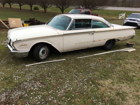 1960 Ford Starliner - Side view of a 1960 Ford Starliner coupe with trim removed, parked outdoors.