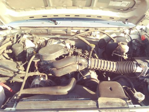 1996 Ford Bronco - The engine bay of a vehicle, showing various components including the air intake system and alternator.