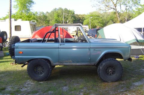 1974 Ford Bronco - A blue 1974 Ford Bronco is parked outdoors with a roll cage and spare tire visible.