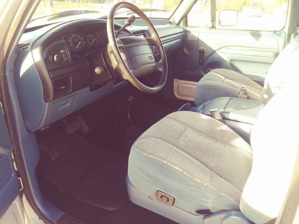 Interior view of a light blue vehicle with cloth seats and a dashboard