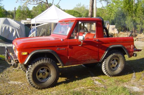 1974 Ford Bronco - Red 1974 Ford Bronco parked outdoors with tents in the background.