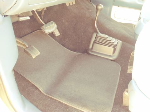 1996 Ford Bronco - The interior of a vehicle shows the brake, clutch, and gas pedals along with a manual transmission shifter.