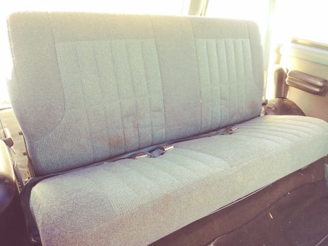 1996 Ford Bronco - Rear bench seat interior of a vehicle, showing fabric upholstery and a seatbelt.
