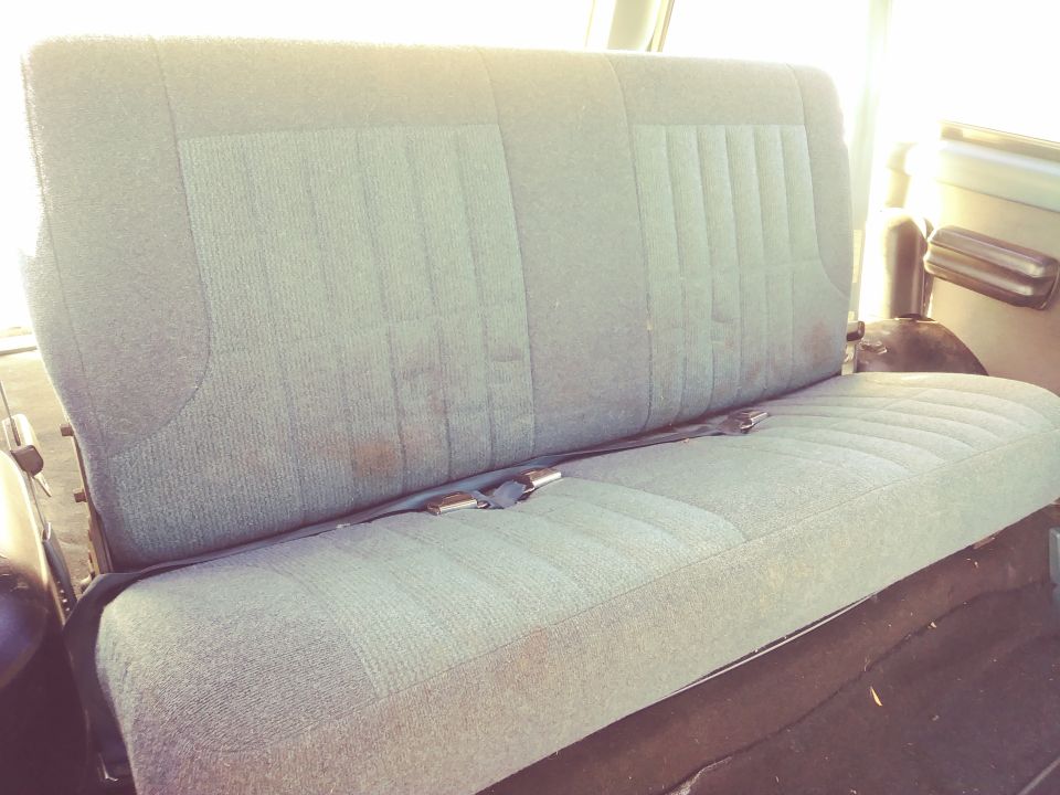 Interior rear bench seat with blue-green fabric and seatbelt