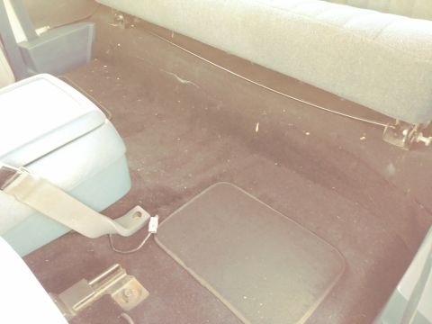 1996 Ford Bronco - The rear floor of a vehicle's interior, showing the carpet and seatbelt hardware.