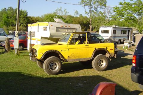 1974 Ford Bronco - A yellow Ford Bronco is parked in a yard with RVs in the background.