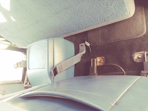 1996 Ford Bronco - Close-up view of the interior of a vehicle, focusing on a seatbelt mechanism and surrounding components.