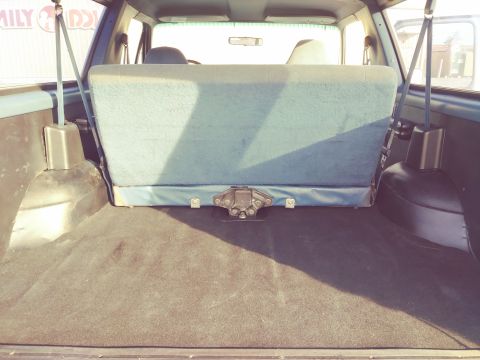 1996 Ford Bronco - The rear cargo space of an SUV is shown, a folded rear seat and carpeted floor.