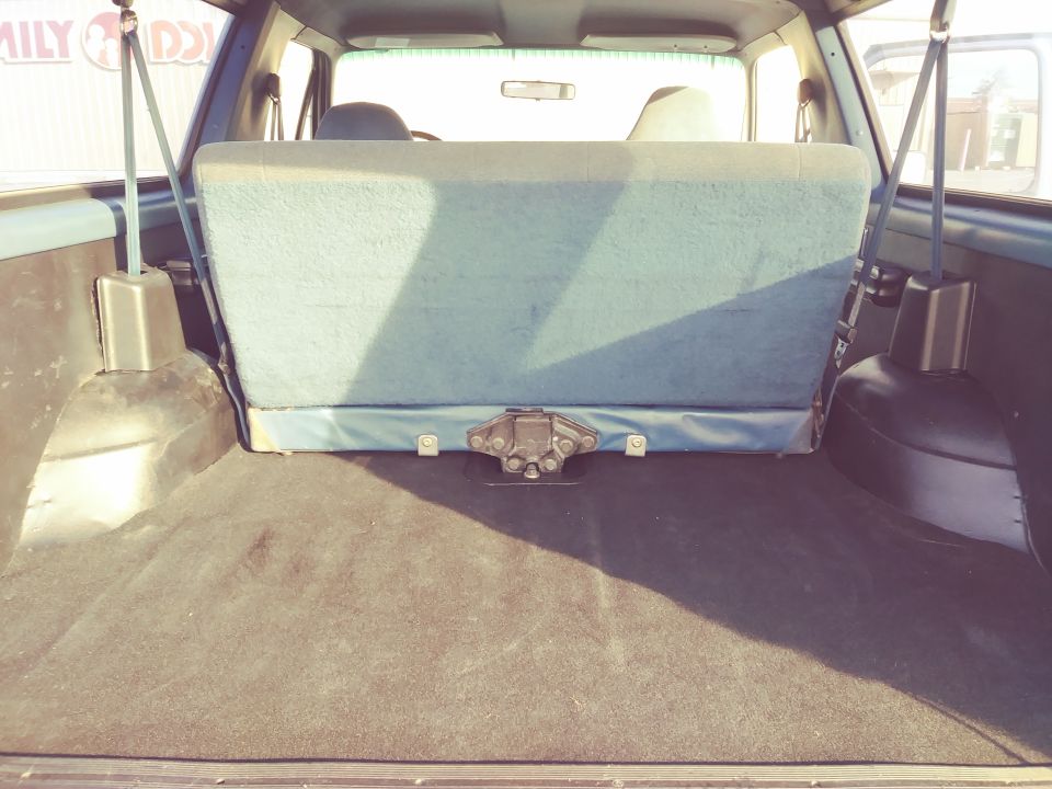 Back cargo area of an SUV with folded-down rear seat. Carpeted floor and side panels visible