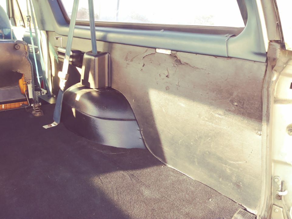 Interior cargo area of a 1996 Ford Bronco showing the wheel well and worn paneling