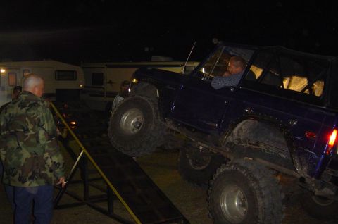 1974 Ford Bronco - A dark blue 1974 Ford Bronco is driven up a ramp at night, with people watching.