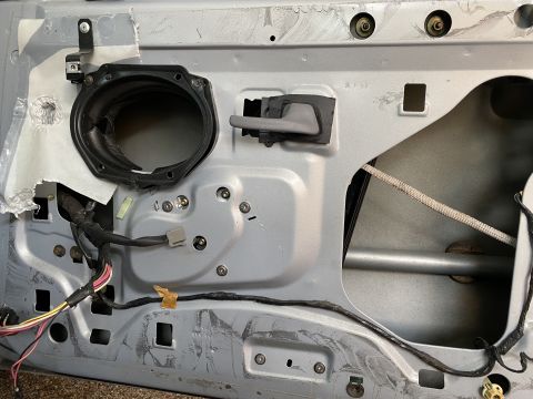 1994 Ford Crown Victoria - The interior of a car door panel is visible, revealing the speaker mount and door handle mechanism.