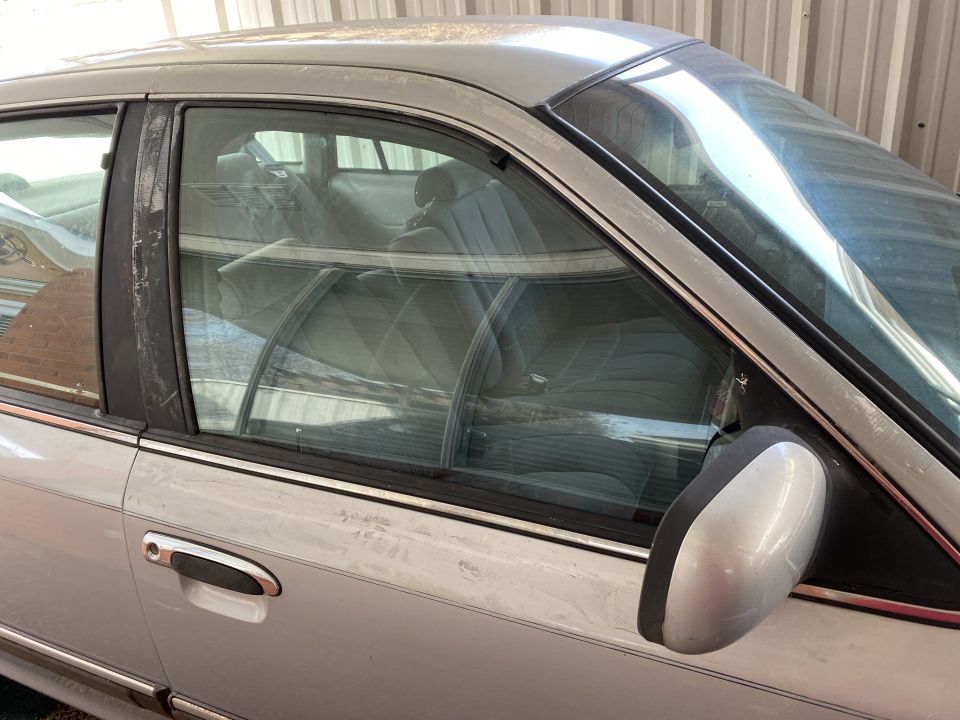 Silver sedan's interior and side view, showing fabric seats and a side mirror