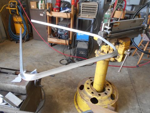 1992 Ford Bronco - A metal strip is being shaped on a roller bending machine in a workshop setting.