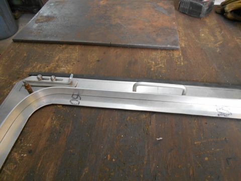 1992 Ford Bronco - Close-up of a metal frame part with a handle and screws, resting on a wooden surface.