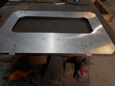 1992 Ford Bronco - This aluminum panel with a large cutout is shown on a workbench, with various tools and a jack in the background.
