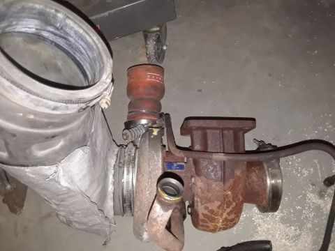 1994 Ford Bronco - A rusty turbocharger and a damaged intake pipe are shown on a concrete floor.