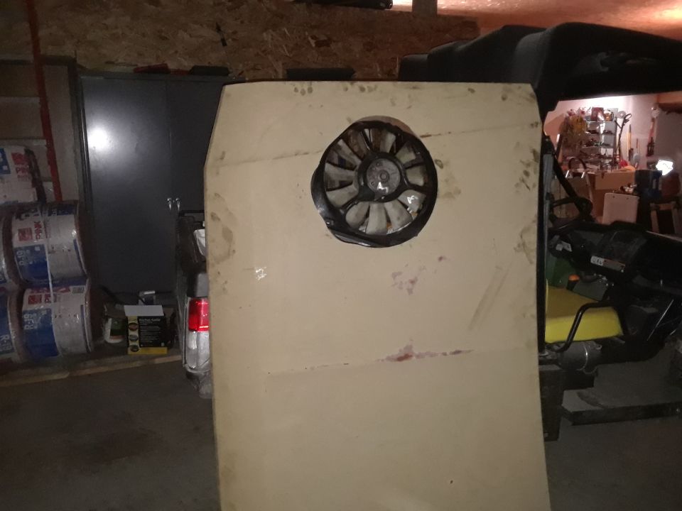 Large panel with fan cutout in front of a vehicle in a garage.