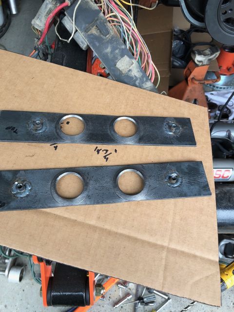 1992 Jeep Wrangler - Two metal plates with two circular cutouts each are laid on a piece of cardboard. Markings on the plates indicate measurements and orientat…