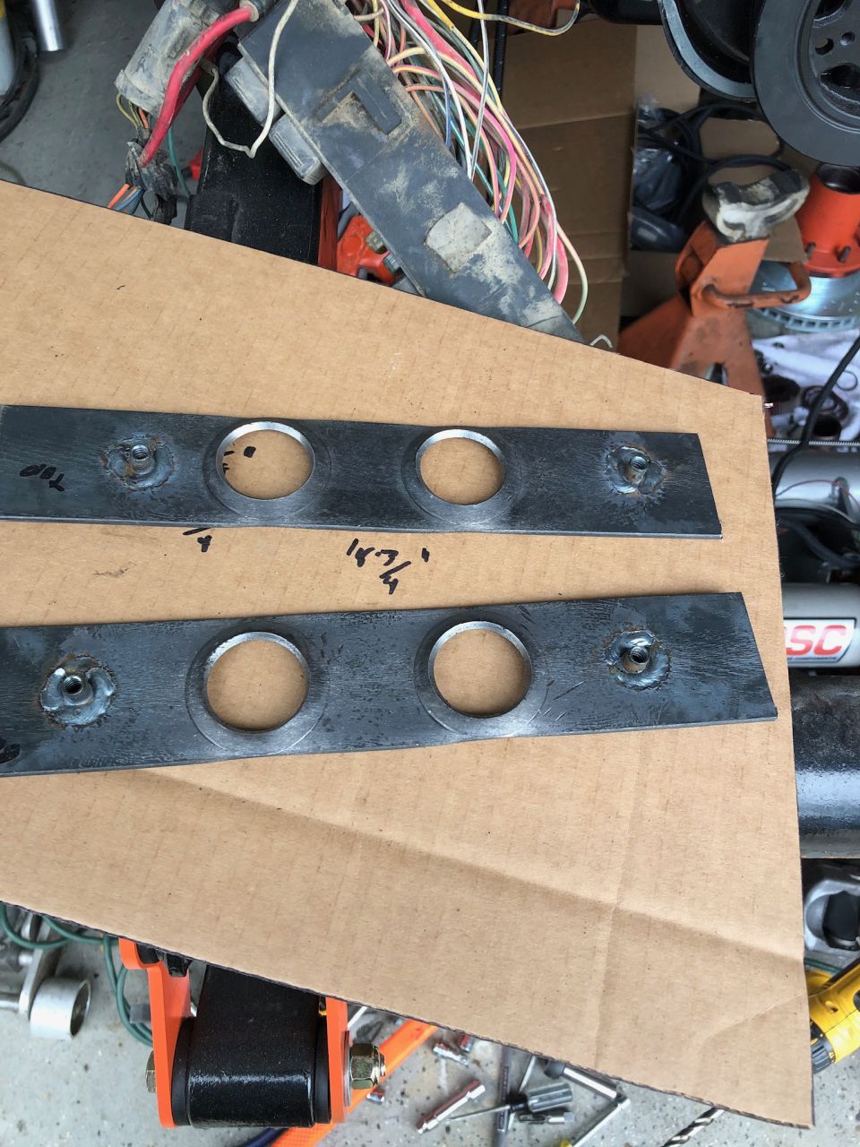 Two metal plates with circular cutouts and markings on cardboard.
