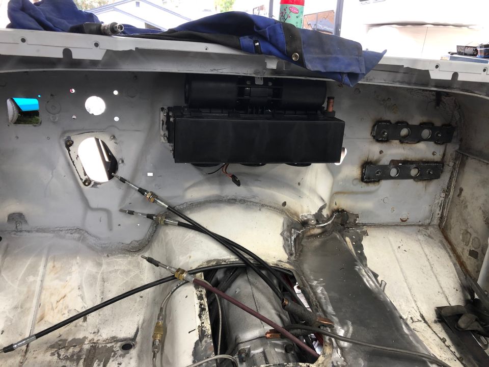 Vehicle firewall interior with HVAC unit and control cables.