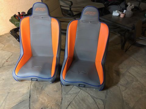 1992 Jeep Wrangler - Two PRP racing seats with gray and orange upholstery and blue piping are displayed on a stone floor.