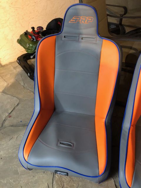 1992 Jeep Wrangler - A pair of custom PRP racing seats with gray, orange, and blue accents are shown in a garage setting with a green toy Jeep in the background.