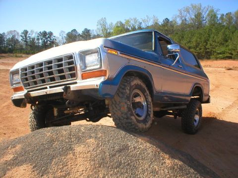 1978 Ford Bronco - This 1978 Ford Bronco is shown off-road on a dirt track with trees in the background.