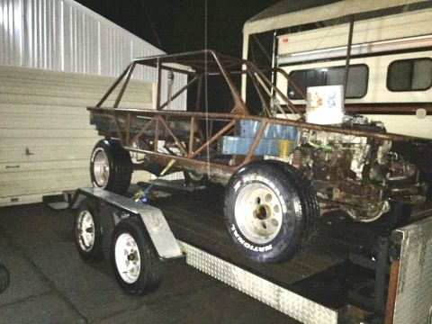 1985 Toyota Hilux - A custom-built, tube-frame race car chassis with an engine is loaded onto a trailer. The vehicle has a roll cage and is parked in front of…