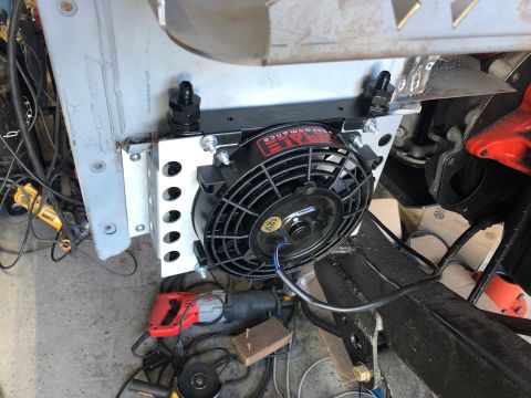 1992 Jeep Wrangler - A close-up view shows an aftermarket oil cooler with a fan mounted to the front of a vehicle frame. The cooler has two black AN fittings an…
