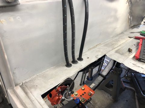 1992 Jeep Wrangler - Three braided hoses are routed through holes in a light gray metal surface, likely part of a vehicle's chassis. Below, an orange brake cali…
