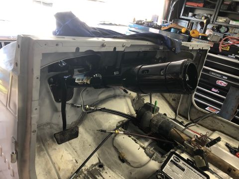 1992 Jeep Wrangler - The interior of a vehicle undergoing work, showing the steering column, pedals, and dashboard area. A black steering column shroud is promi…