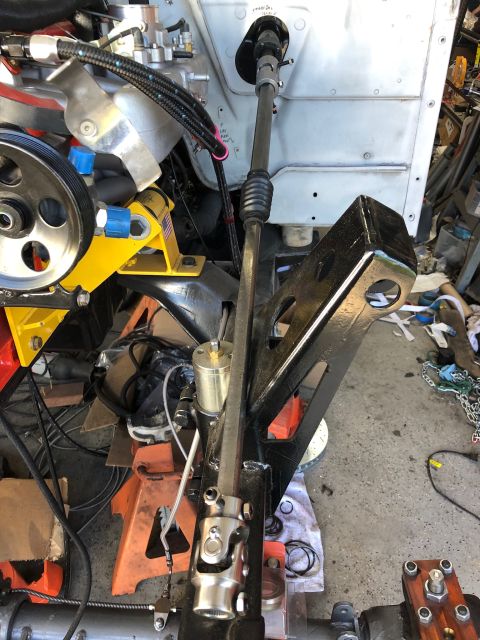 1992 Jeep Wrangler - A close-up view of a steering column and linkage assembly, likely part of a vehicle modification project, with engine components and jack s…