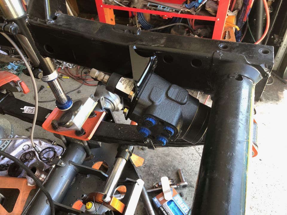 Close-up of a black power steering gearbox mounted to a vehicle frame.